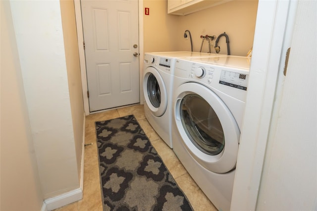 laundry room with independent washer and dryer and light tile patterned floors