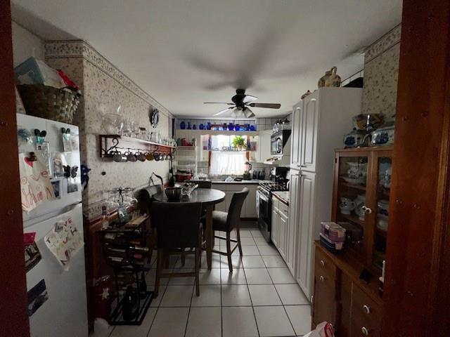 kitchen with white cabinets, light tile patterned floors, stainless steel appliances, and ceiling fan