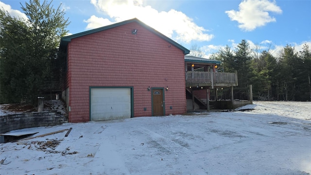 view of snow covered exterior with a wooden deck, a balcony, and a garage