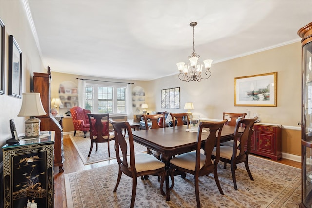 dining area with baseboards, light wood finished floors, a chandelier, and crown molding