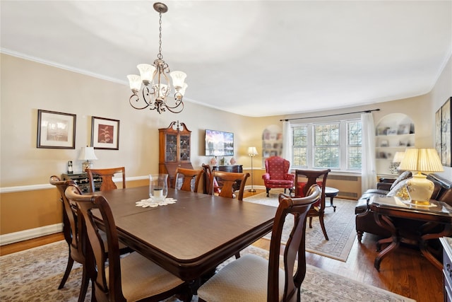 dining area with crown molding, baseboards, a chandelier, and wood finished floors