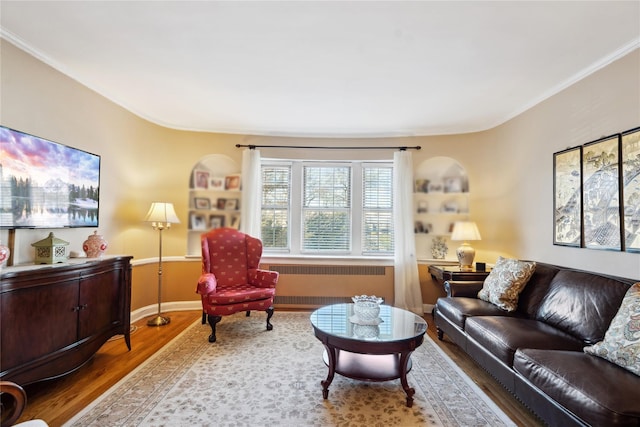 living area featuring ornamental molding, radiator, baseboards, and wood finished floors