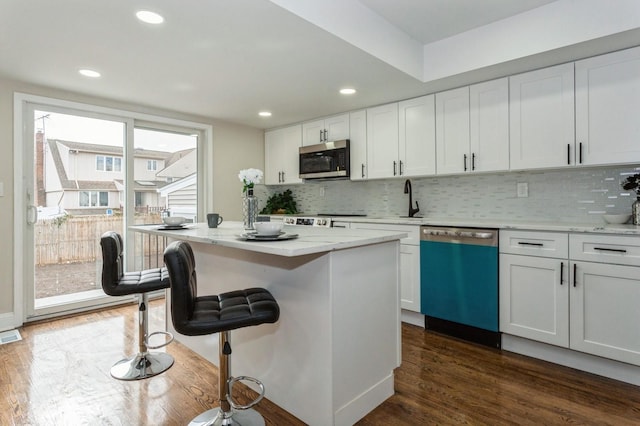 kitchen featuring a kitchen island, decorative backsplash, light stone countertops, stainless steel appliances, and white cabinets