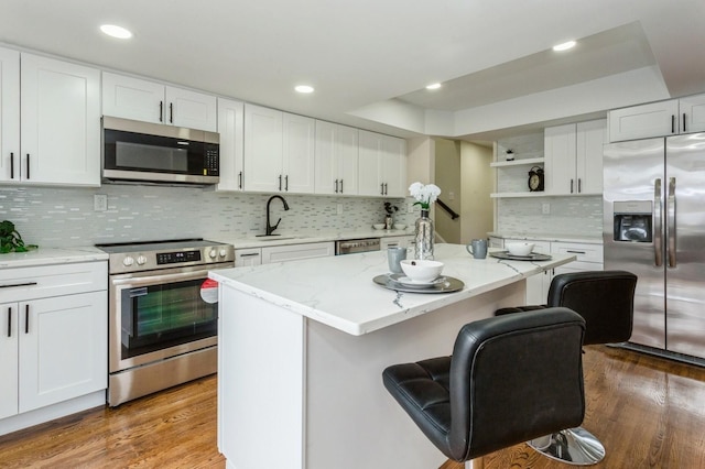 kitchen featuring white cabinetry, stainless steel appliances, dark wood-type flooring, a kitchen island, and sink