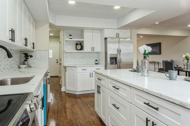 kitchen featuring appliances with stainless steel finishes, white cabinetry, light stone counters, and sink