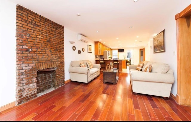 living room with a brick fireplace, a wall unit AC, and dark wood-type flooring