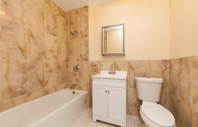 full bathroom with tiled shower / bath combo, toilet, tile walls, and vanity