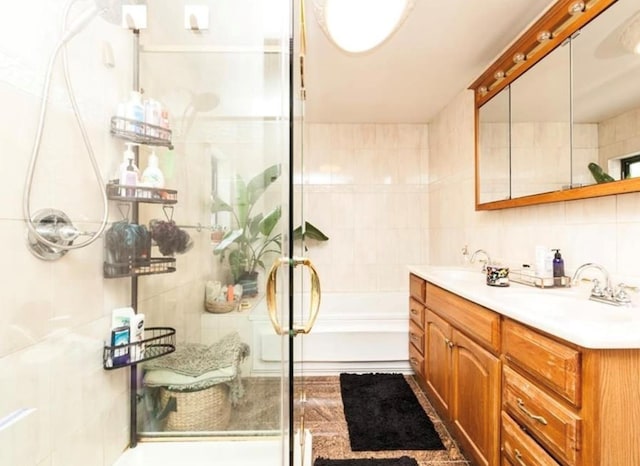 bathroom with vanity, shower with separate bathtub, and tile walls