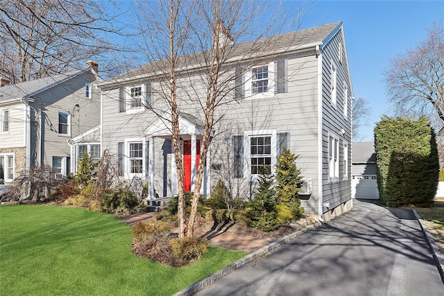 colonial inspired home with a garage, an outbuilding, and a front yard