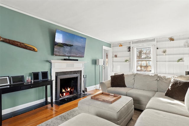 living room featuring hardwood / wood-style flooring, a brick fireplace, and crown molding