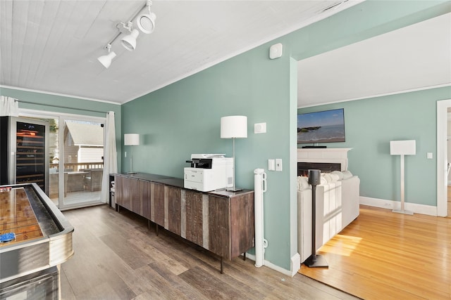 kitchen featuring crown molding, beverage cooler, track lighting, and wood-type flooring