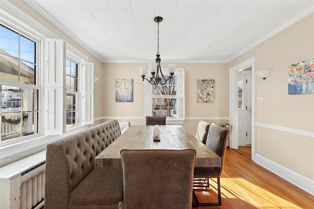 dining space featuring light hardwood / wood-style floors, an inviting chandelier, and crown molding