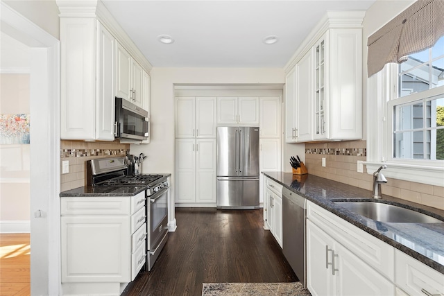 kitchen with dark stone counters, sink, appliances with stainless steel finishes, dark hardwood / wood-style flooring, and white cabinetry