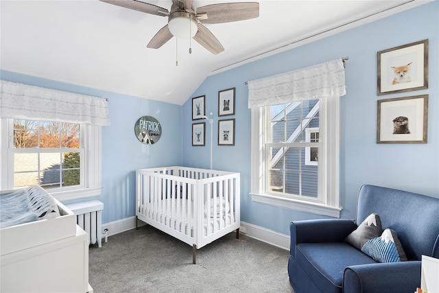 carpeted bedroom featuring ceiling fan, multiple windows, a nursery area, and vaulted ceiling