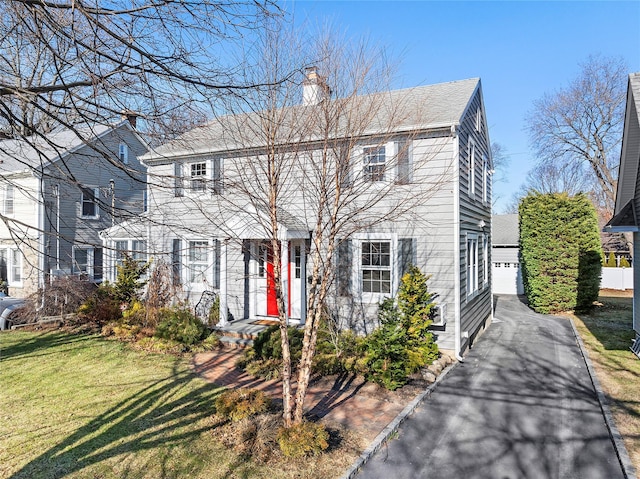 colonial home featuring a front yard, a garage, and an outdoor structure