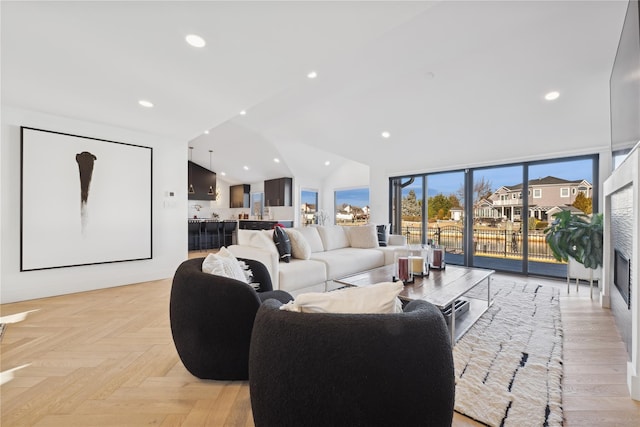 living room featuring lofted ceiling, light parquet floors, and a wall of windows