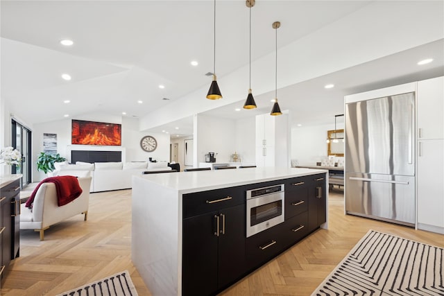 kitchen featuring decorative light fixtures, built in appliances, a kitchen island, and light parquet floors