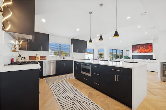 kitchen featuring sink, a center island, vaulted ceiling, hanging light fixtures, and appliances with stainless steel finishes