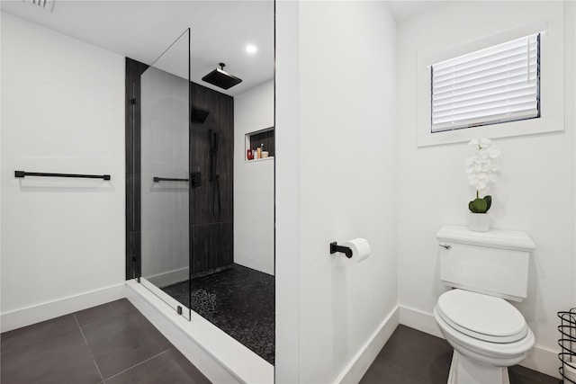 bathroom featuring toilet, tile patterned flooring, and tiled shower