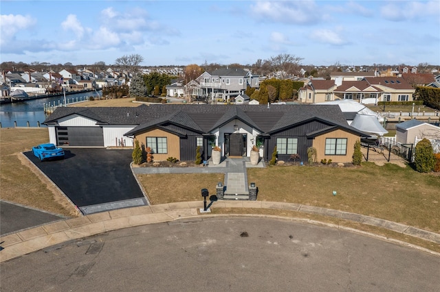 view of front of home with a front lawn, a garage, and a water view