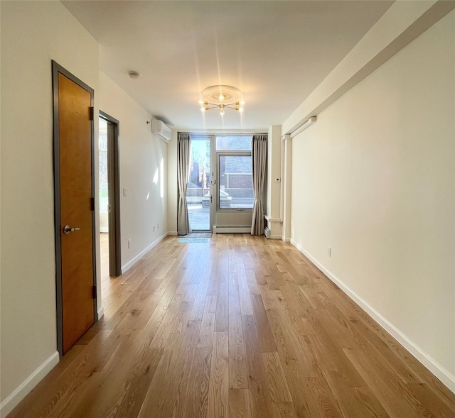 empty room featuring an AC wall unit, a baseboard radiator, and light hardwood / wood-style floors