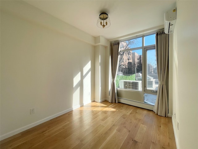 spare room with a baseboard heating unit and light hardwood / wood-style flooring