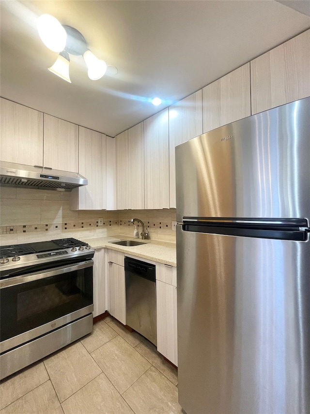 kitchen with stainless steel appliances, light tile patterned floors, sink, and backsplash