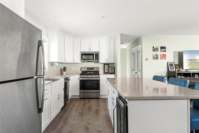 kitchen with a kitchen island, white cabinetry, stainless steel appliances, and beverage cooler