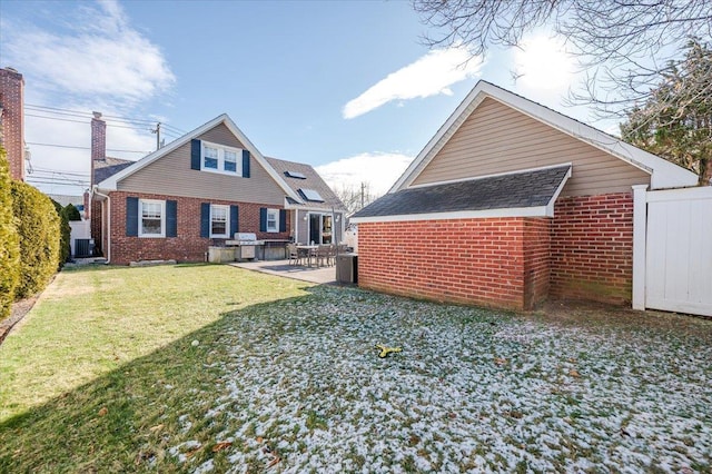 rear view of house with central AC, a patio area, and a lawn