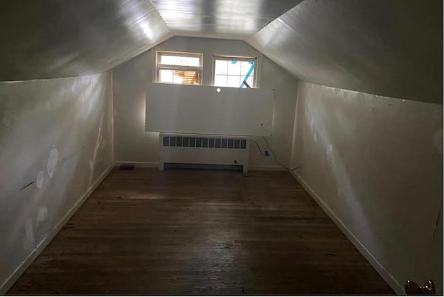 additional living space featuring dark wood-type flooring, radiator, and vaulted ceiling