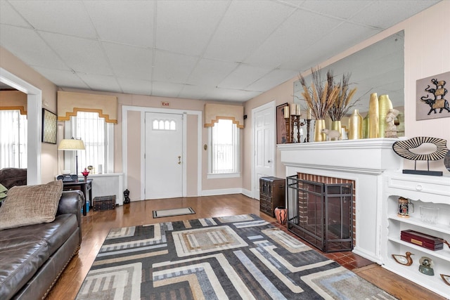 living room featuring a drop ceiling, a fireplace, and a wealth of natural light