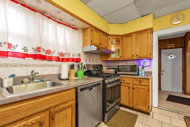 kitchen featuring appliances with stainless steel finishes, backsplash, a paneled ceiling, sink, and light tile patterned floors