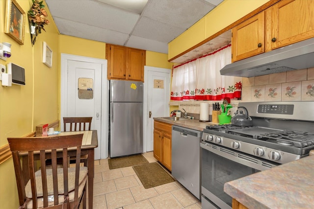 kitchen with light tile patterned flooring, stainless steel appliances, a drop ceiling, and sink