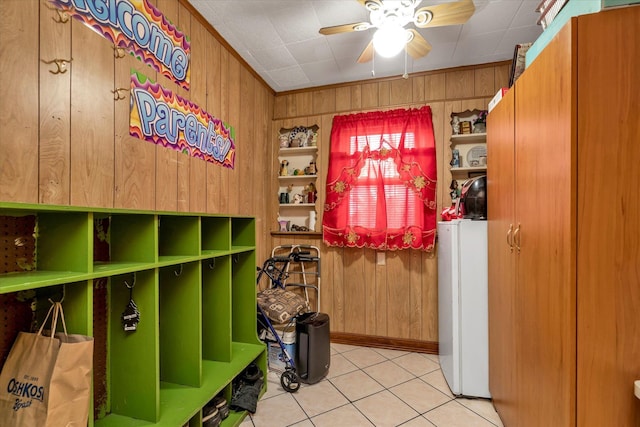 mudroom featuring ceiling fan, wooden walls, and light tile patterned flooring