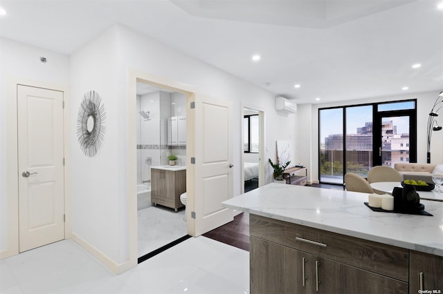 full bathroom featuring a wall mounted air conditioner, vanity, tile patterned floors, bath / shower combo with glass door, and toilet