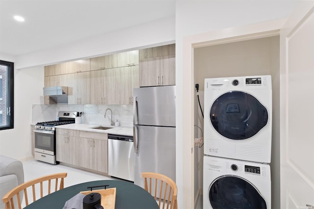 kitchen with light brown cabinets, sink, stacked washer / dryer, and stainless steel appliances