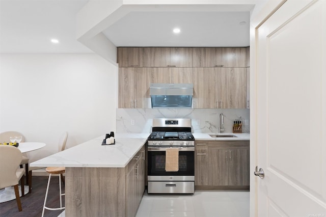 kitchen featuring light stone countertops, kitchen peninsula, backsplash, gas range, and sink