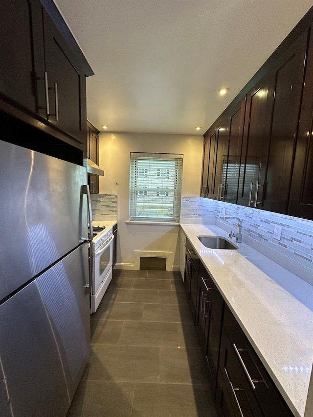 kitchen with exhaust hood, sink, decorative backsplash, stainless steel fridge, and white gas range