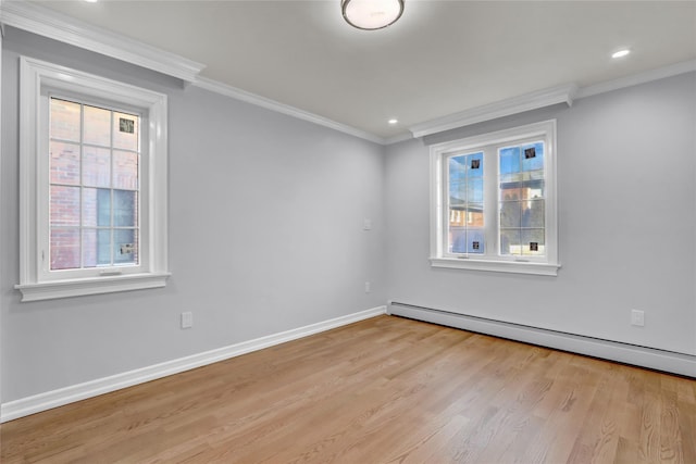 empty room featuring light hardwood / wood-style flooring, baseboard heating, and crown molding