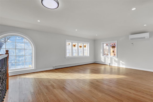 spare room featuring light hardwood / wood-style floors, a baseboard radiator, and a wall mounted AC