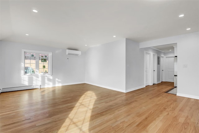 empty room featuring an AC wall unit, a baseboard heating unit, and light wood-type flooring