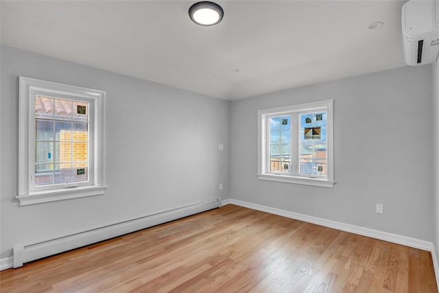 unfurnished room featuring a wall unit AC, light wood-type flooring, a wealth of natural light, and a baseboard radiator