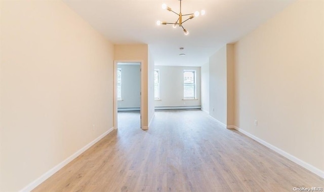 unfurnished room with a chandelier, a baseboard heating unit, and light wood-type flooring