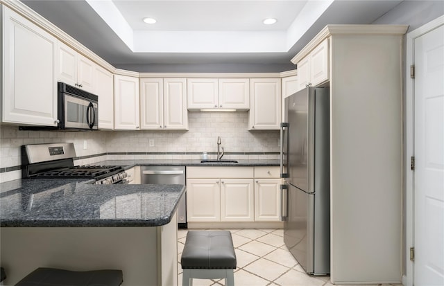 kitchen with kitchen peninsula, a kitchen breakfast bar, stainless steel appliances, sink, and light tile patterned floors