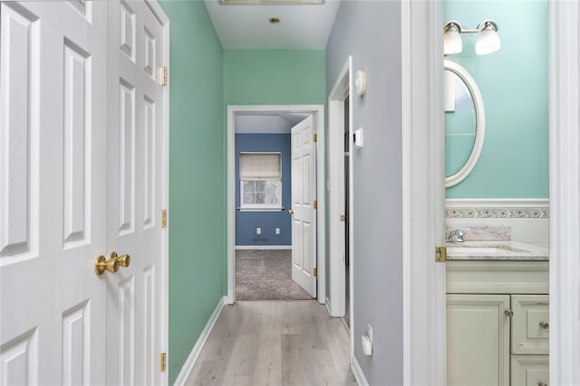 hallway featuring sink and light hardwood / wood-style floors