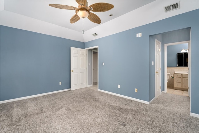 unfurnished bedroom with ensuite bathroom, vaulted ceiling, ceiling fan, and light colored carpet