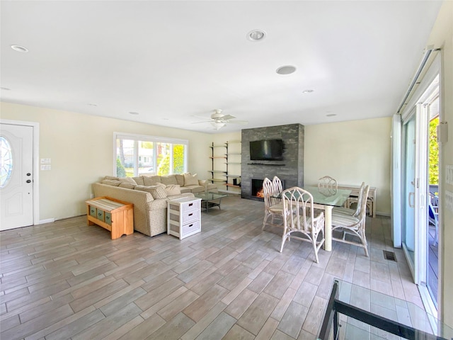 living room featuring ceiling fan and a large fireplace