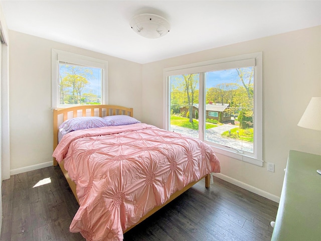 bedroom with dark hardwood / wood-style floors and multiple windows