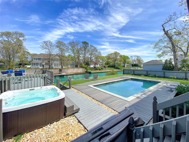 view of pool featuring a deck with water view and a hot tub