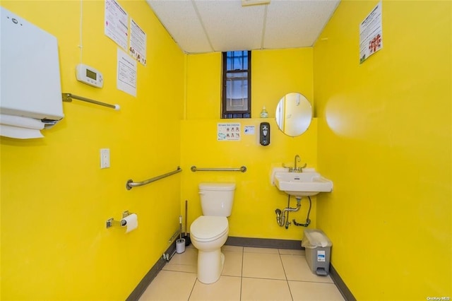 bathroom featuring toilet, a paneled ceiling, tile patterned floors, and sink